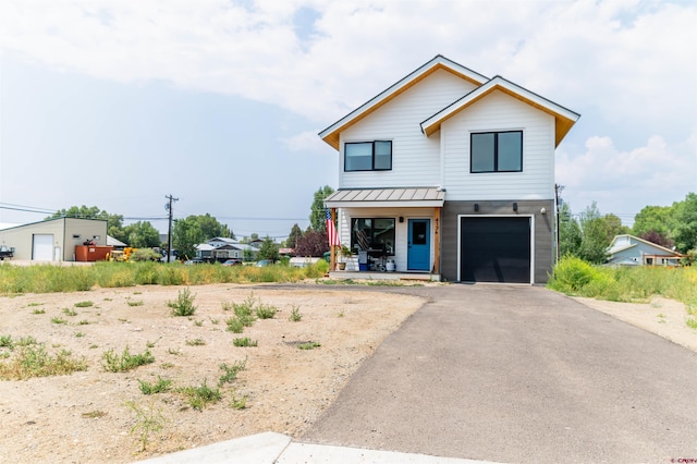 view of front of home featuring metal roof, aphalt driveway, an attached garage, a standing seam roof, and a porch