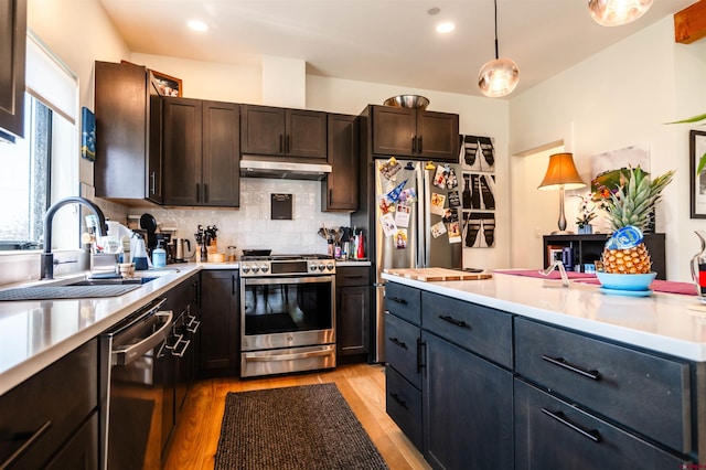 kitchen with stainless steel appliances, a sink, light countertops, and under cabinet range hood