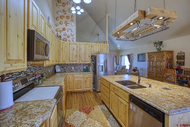 kitchen featuring light brown cabinetry, sink, decorative backsplash, a kitchen island with sink, and stainless steel appliances