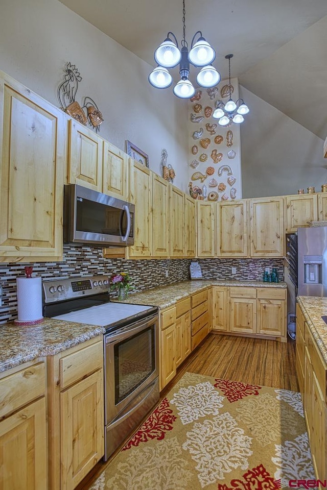 kitchen featuring decorative backsplash, stainless steel appliances, and hanging light fixtures