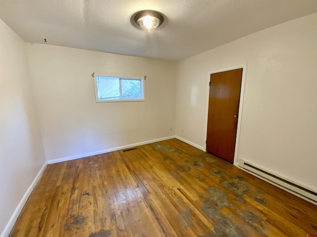 empty room featuring dark hardwood / wood-style floors and a baseboard heating unit