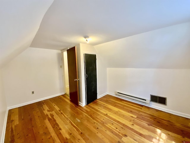 additional living space with a baseboard radiator, lofted ceiling, and hardwood / wood-style floors