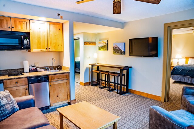 kitchen featuring a ceiling fan, a sink, black microwave, light carpet, and dishwasher