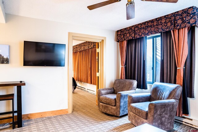 living area featuring baseboards, baseboard heating, ceiling fan, and carpet flooring