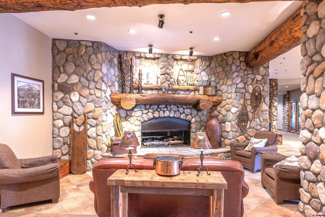 living room with beam ceiling, a stone fireplace, and recessed lighting