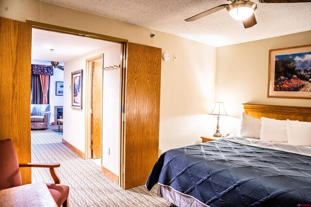 bedroom with a textured ceiling, ceiling fan, and light colored carpet