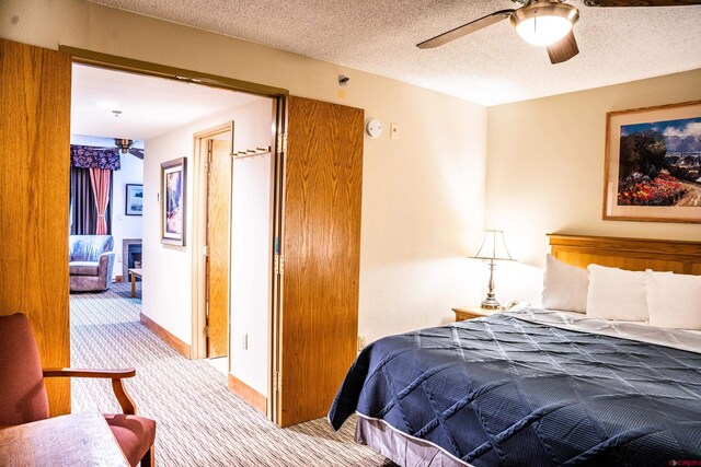 carpeted bedroom featuring baseboards, a textured ceiling, and a ceiling fan