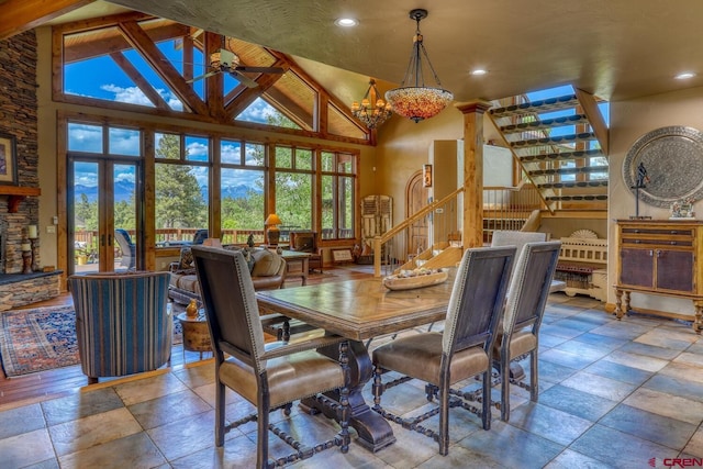 dining space featuring decorative columns, ceiling fan with notable chandelier, light tile patterned floors, and high vaulted ceiling