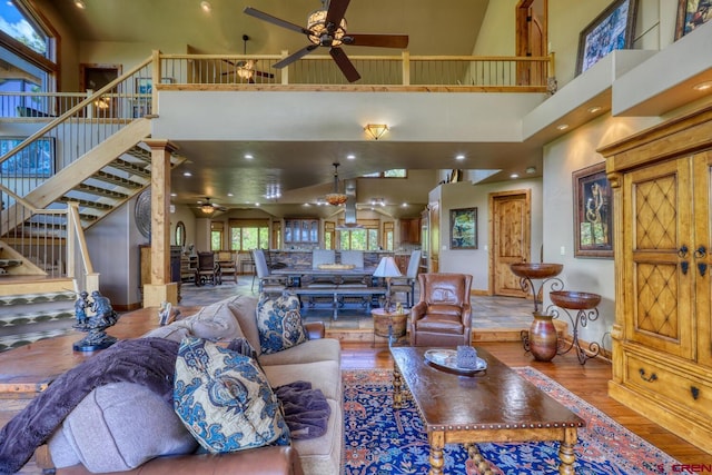 living room with wood-type flooring, ceiling fan, and a high ceiling