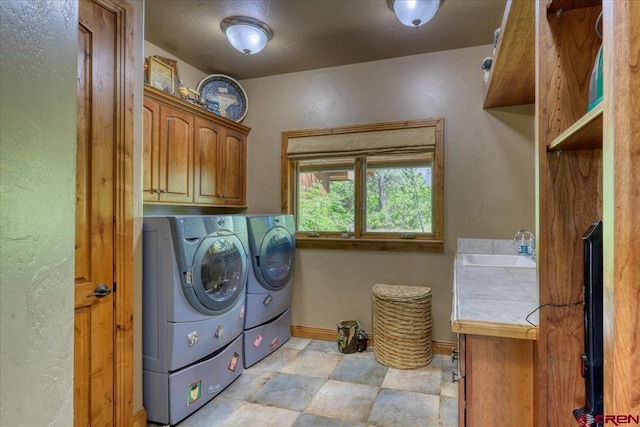 laundry room with light tile patterned floors, washing machine and dryer, sink, and cabinets