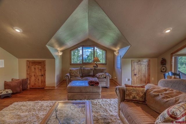 living room featuring light wood-type flooring, lofted ceiling, and plenty of natural light