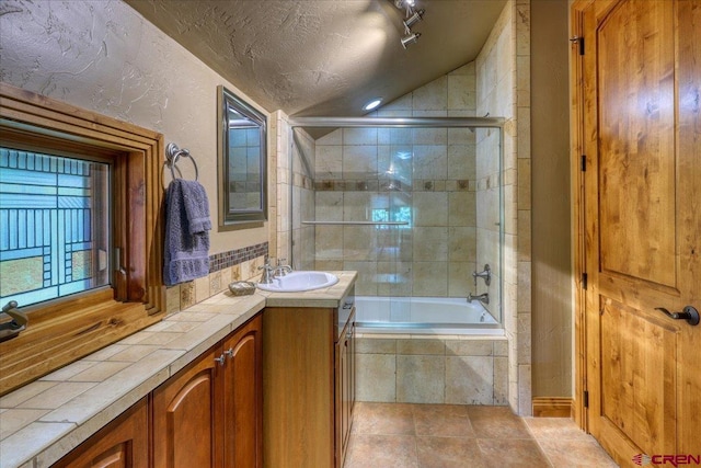 387 Bristlecone Dr, Pagosa Springs, CO 81147 - bathroom featuring lofted ceiling, a textured ceiling, a textured wall, tiled shower / bath, and vanity