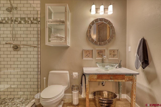 bathroom with vanity, a tile shower, and toilet