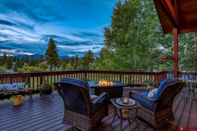 deck at dusk featuring an outdoor living space with a fire pit