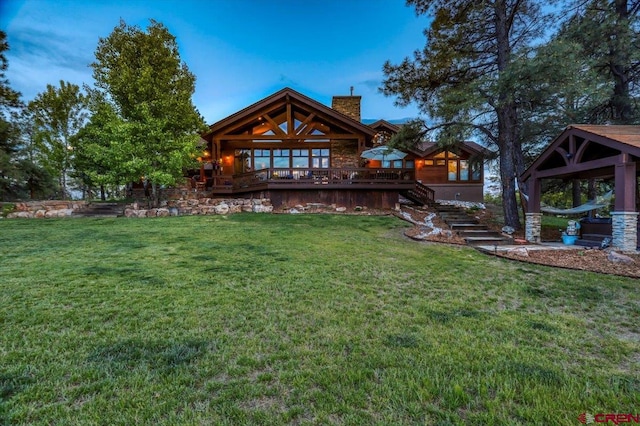 rear view of property with a gazebo, a deck, and a lawn