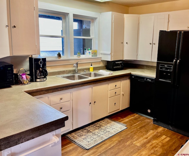 kitchen with black appliances, white cabinetry, and sink