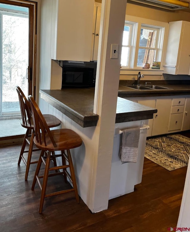 kitchen featuring a wealth of natural light, sink, white cabinets, and dark hardwood / wood-style floors