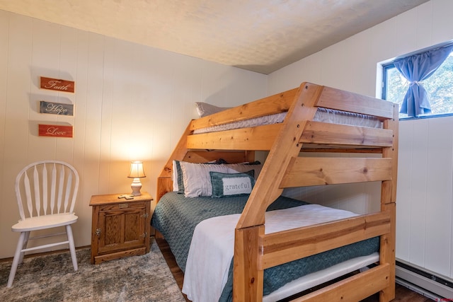 bedroom featuring dark wood-type flooring, wood walls, and baseboard heating