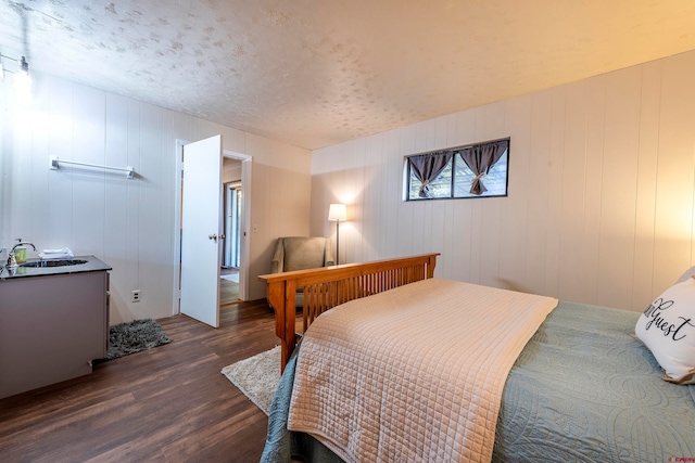 bedroom featuring dark hardwood / wood-style flooring, a textured ceiling, and sink