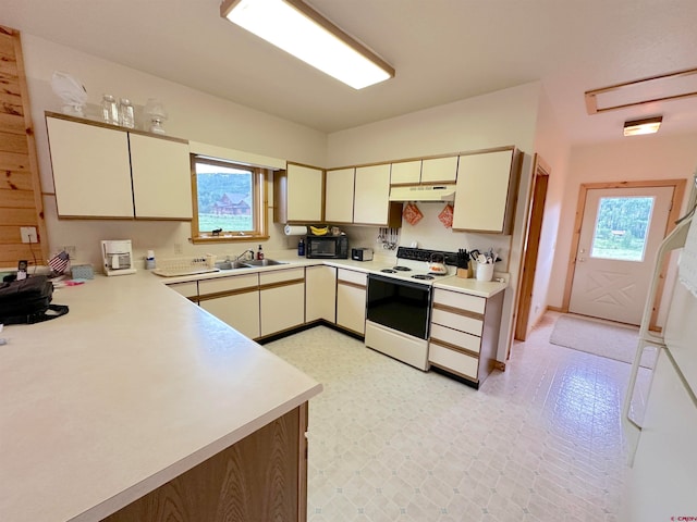 kitchen with white appliances, light tile patterned floors, kitchen peninsula, cream cabinetry, and sink