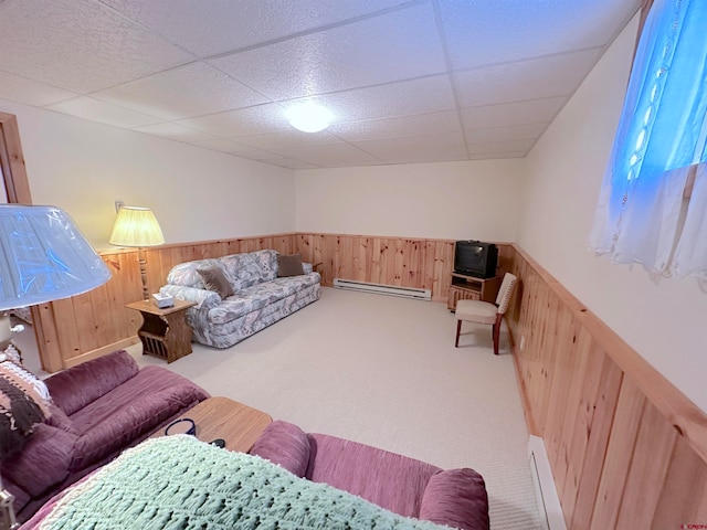 carpeted living room featuring wooden walls, a paneled ceiling, and baseboard heating