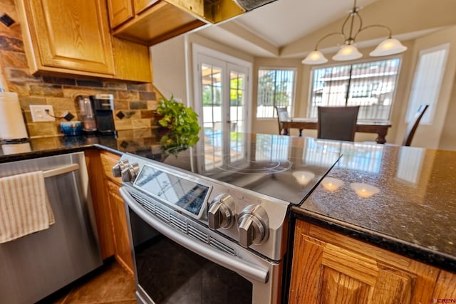 kitchen with french doors, stainless steel appliances, lofted ceiling, tasteful backsplash, and dark stone countertops