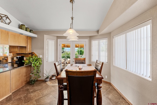 dining space with vaulted ceiling, stone finish flooring, french doors, and baseboards