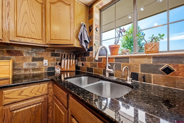 kitchen with tasteful backsplash, dark stone counters, and a sink