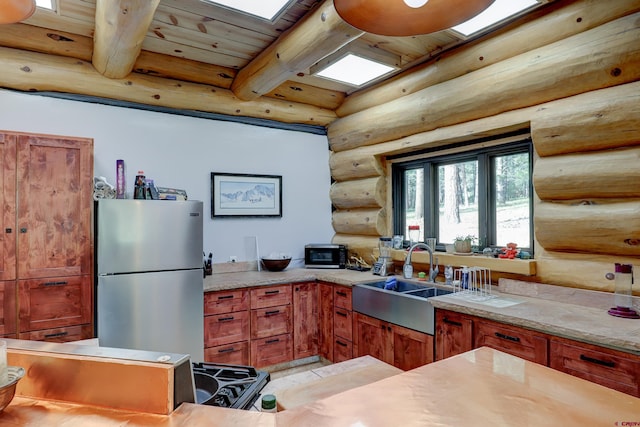 kitchen featuring stainless steel refrigerator, beam ceiling, rustic walls, and wood ceiling