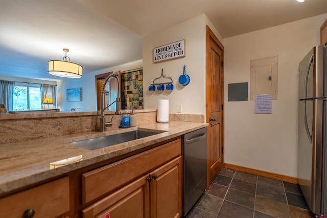 kitchen featuring dark tile patterned floors, stainless steel appliances, light stone countertops, and sink