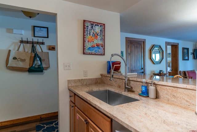 kitchen featuring hardwood / wood-style flooring, sink, and light stone counters