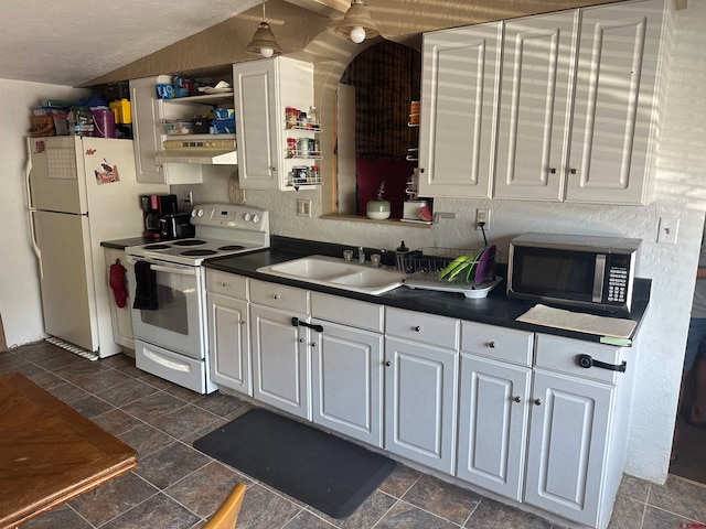 kitchen with dark tile patterned floors, white cabinets, wall chimney exhaust hood, white appliances, and sink