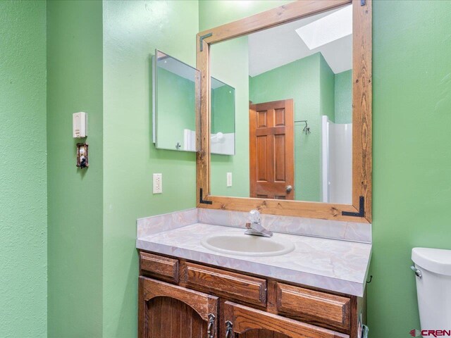 bathroom with vanity, lofted ceiling with skylight, and toilet