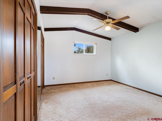 carpeted spare room with ceiling fan, a textured ceiling, and vaulted ceiling