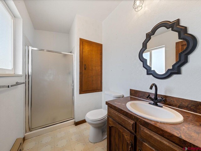 bathroom featuring a shower with door, vanity, tile patterned floors, and toilet