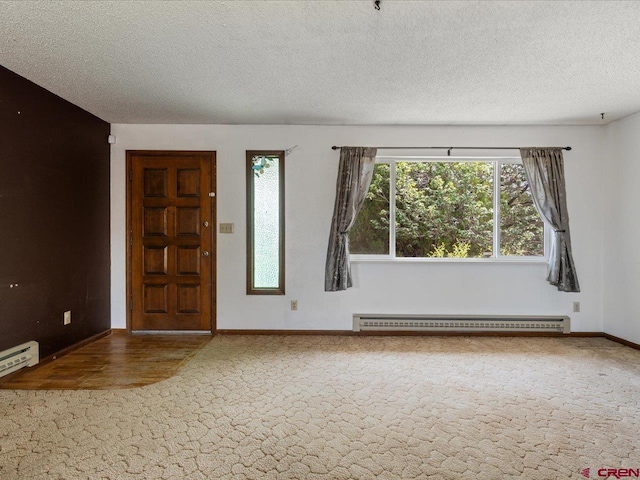 foyer entrance with a textured ceiling, a baseboard radiator, a wealth of natural light, and carpet floors