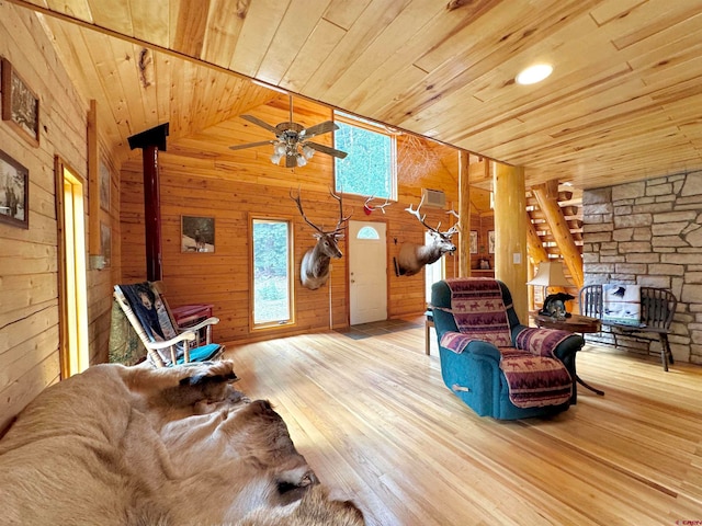 living room featuring ceiling fan, wooden ceiling, light hardwood / wood-style floors, and wood walls