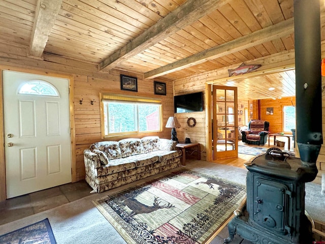 living room with a wood stove, wooden walls, wood ceiling, and beamed ceiling