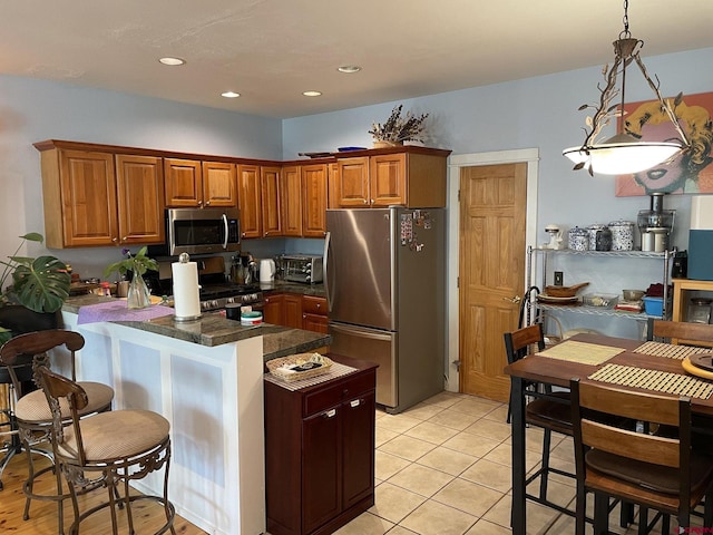 kitchen with light tile patterned floors, stainless steel appliances, and hanging light fixtures