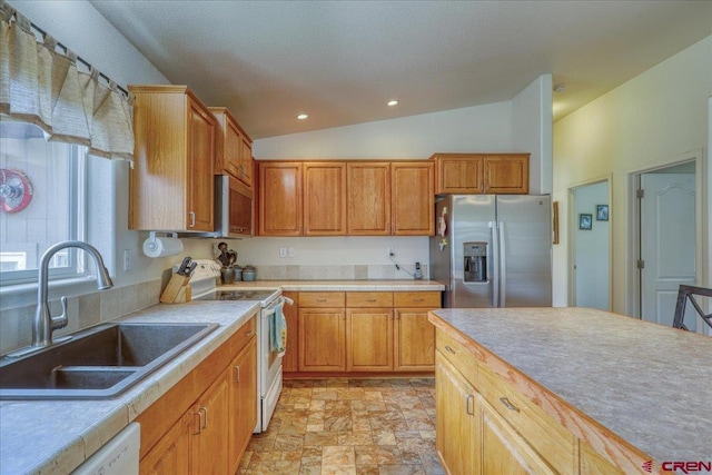 kitchen with light countertops, stone finish flooring, vaulted ceiling, a sink, and white appliances