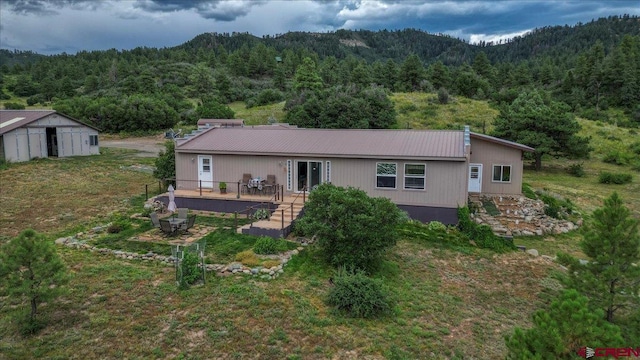 back of house featuring metal roof and a view of trees