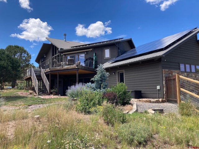 rear view of house with solar panels and a deck