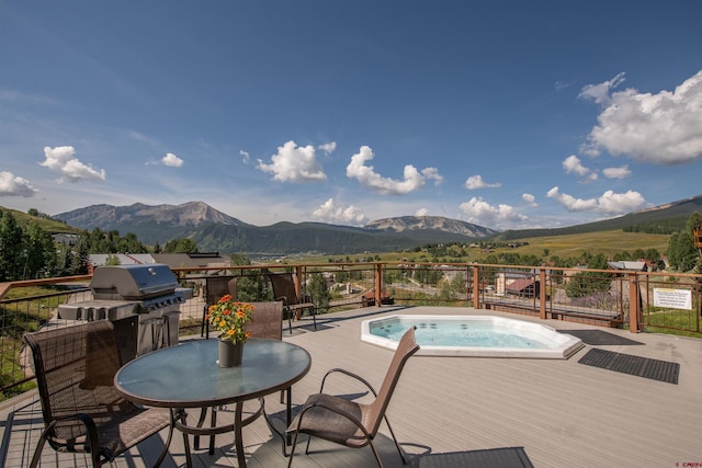 view of pool featuring area for grilling, a deck with mountain view, and an outdoor hot tub