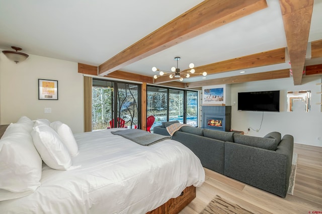 bedroom with beam ceiling, a chandelier, a fireplace, and light hardwood / wood-style floors