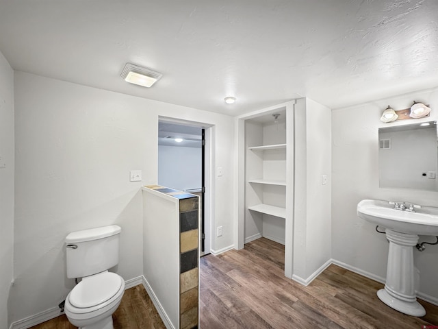 bathroom featuring toilet, sink, and wood-type flooring