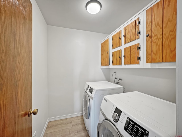 laundry area with light wood-type flooring, cabinets, and washer and clothes dryer