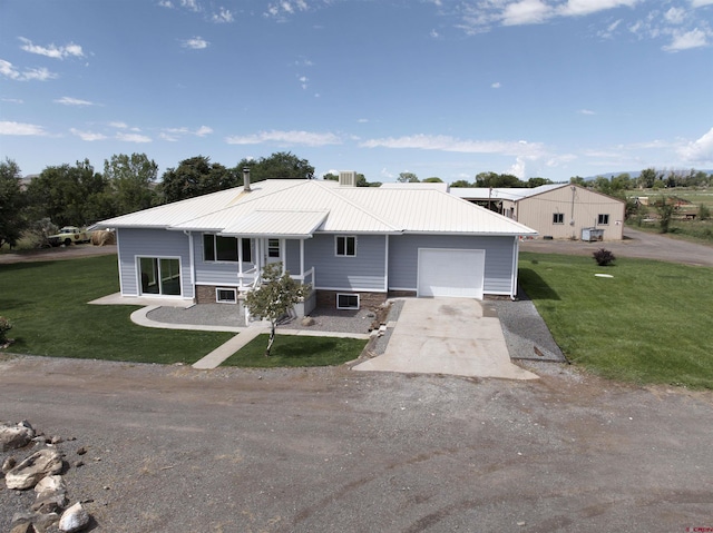 view of front of house with a garage, metal roof, a front yard, and driveway