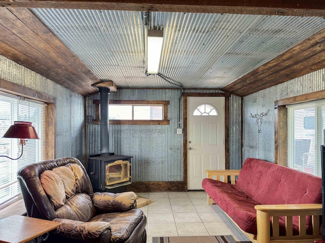 living room with light tile patterned floors, vaulted ceiling, and a wood stove