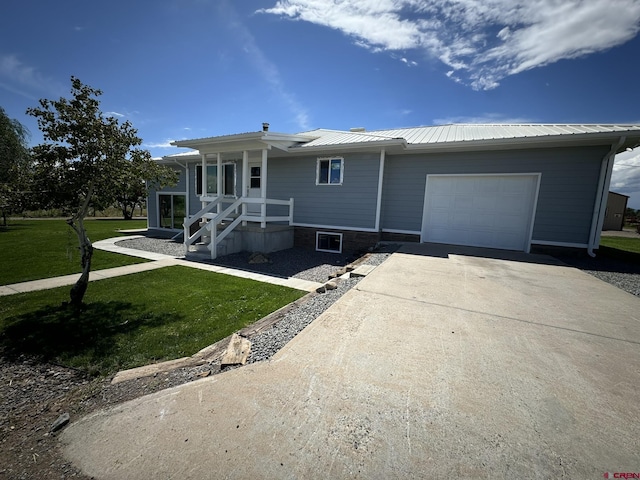 ranch-style house featuring a garage, a front yard, metal roof, and driveway