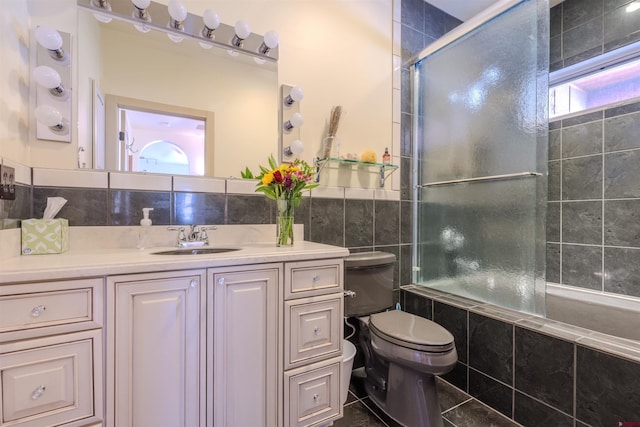 bathroom featuring toilet, tile walls, tasteful backsplash, tile patterned floors, and vanity